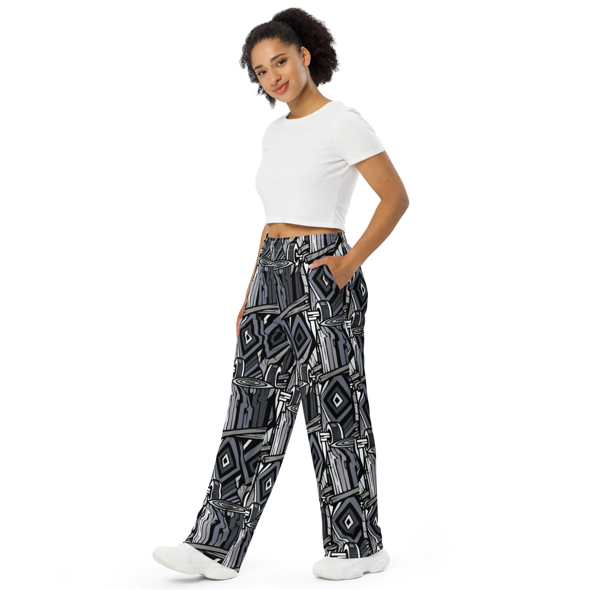 Wide-leg trousers featuring an all-over repeating abstract skateboard and wood-grain graphic pattern rendered in monochrome black, grey, and white tones.