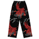 Back side. Wide-leg trousers featuring an abstract graphic of a black shadowed watcher figure riding a grey brick-patterned skateboard with red flowing ribbon-like strands extending downward.