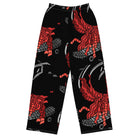 Front. Wide-leg trousers featuring an abstract graphic of a black shadowed watcher figure riding a grey brick-patterned skateboard with red flowing ribbon-like strands extending downward.