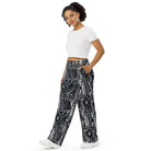 Wide-leg trousers featuring an all-over repeating abstract skateboard and wood-grain graphic pattern rendered in monochrome black, grey, and white tones.